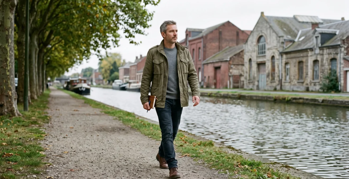 Un homme marche le long d'un canal français avec un petit carnet en main.